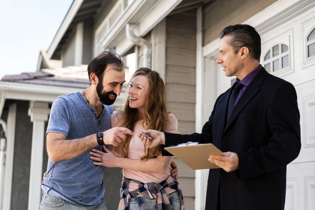Keys being exchanged in front of a house during a rental agreement process.