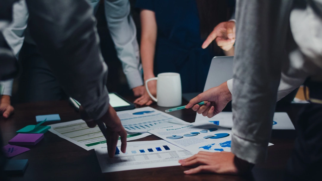 People collaborating over a table with charts, representing car rental business planning.