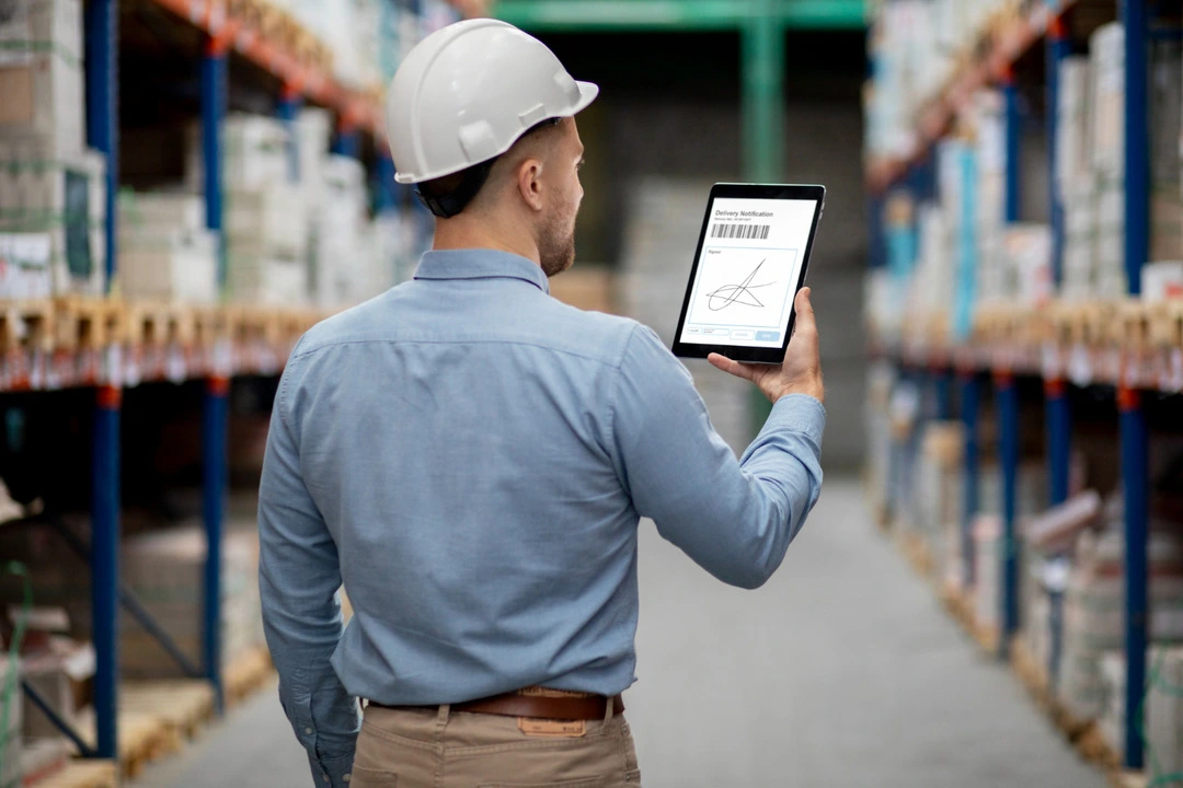 Worker using a tablet in a warehouse for smart tool tracking and inventory.