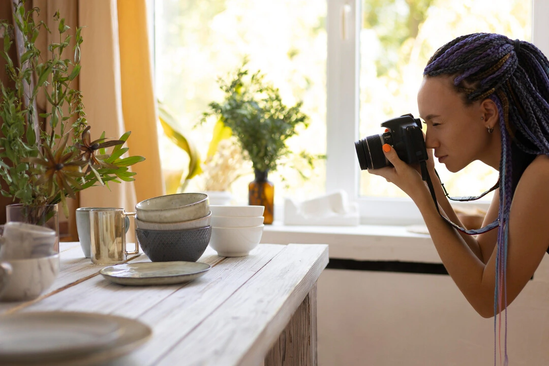 A professional capturing a food table setup with natural light for high-quality photography.