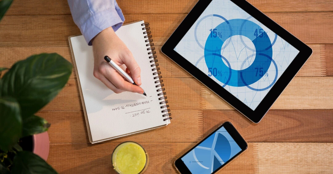 Workspace featuring a notebook, tablet, and phone for strategic business planning.