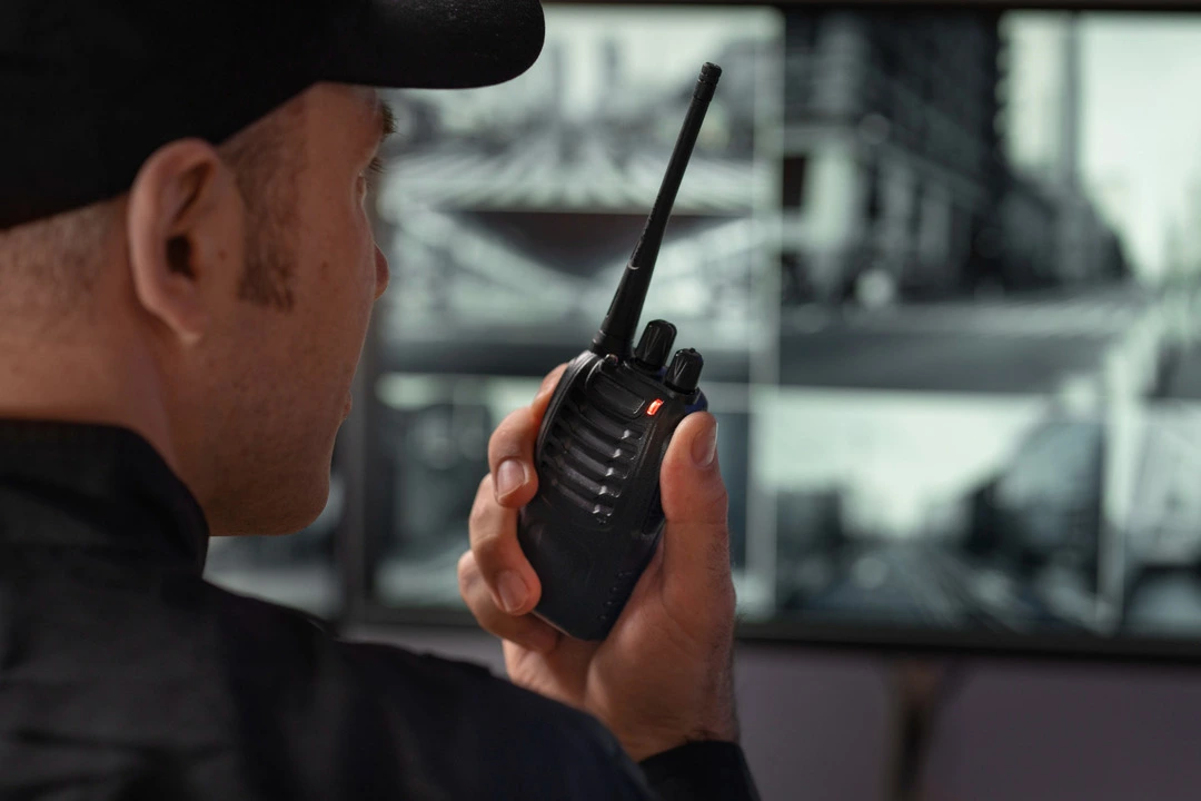 Person monitoring storage security with surveillance feeds and a walkie-talkie.