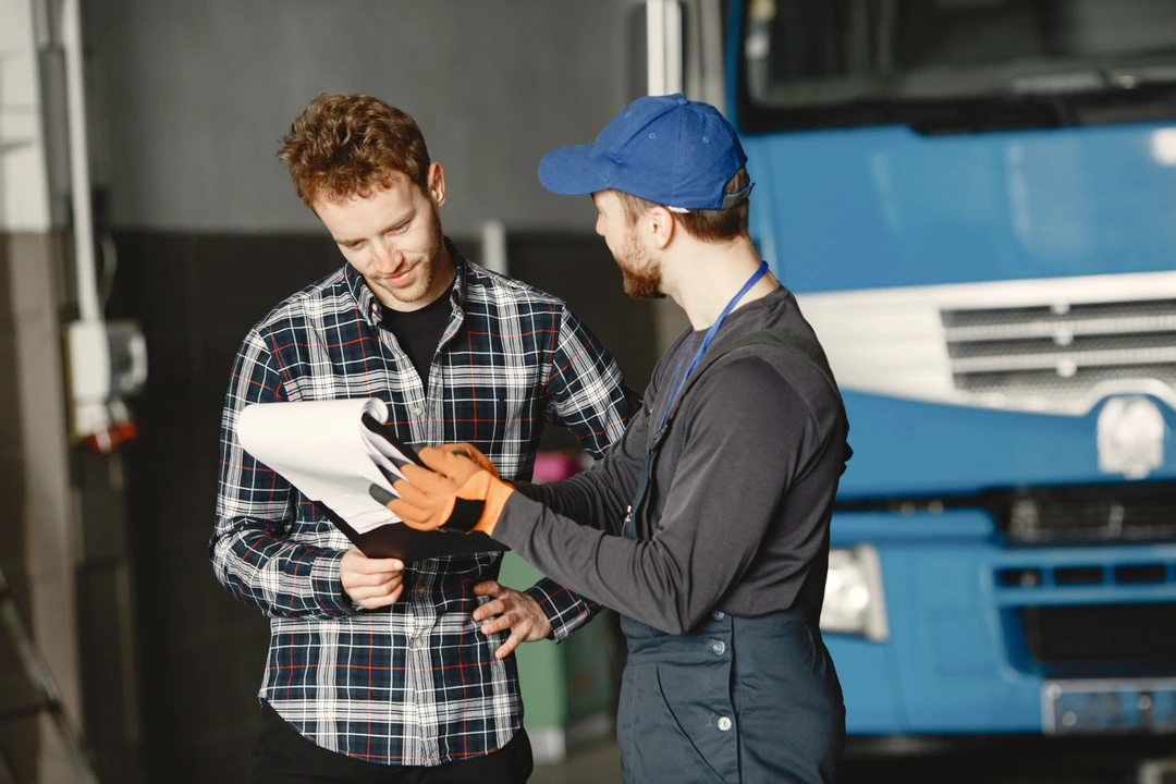 Two people reviewing transportation papers near a parked truck.