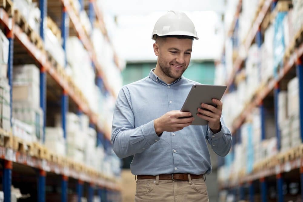 Warehouse worker managing inventory with a tablet for maximum profits in 2025.