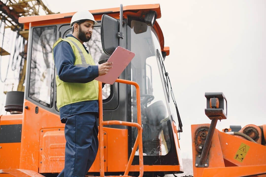 Person inspecting excavator for operating and maintenance costs