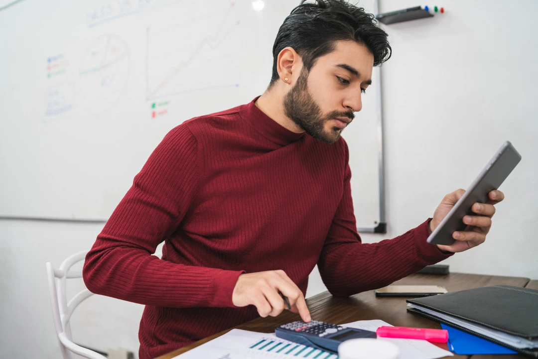 A person using a calculator and tablet to set up a pricing system.