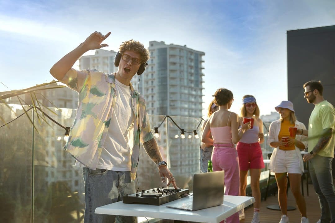 DJ mixing music at a lively rooftop party, showcasing event rental business ideas