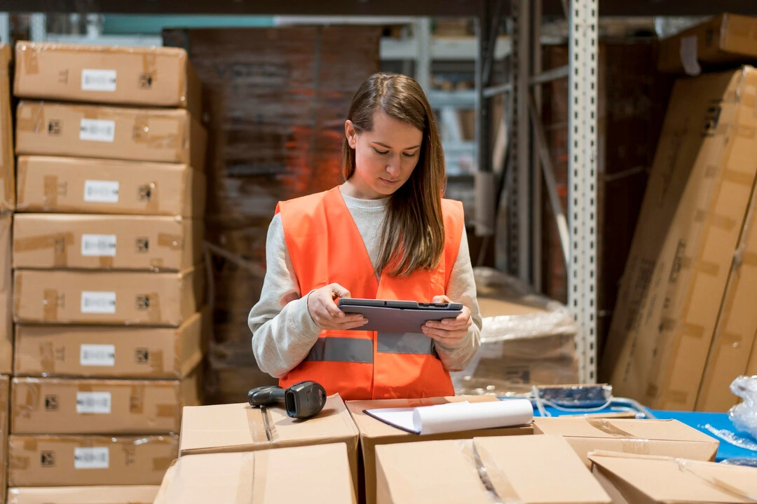 A person using a tablet to manage inventory in a warehouse for a rental business.