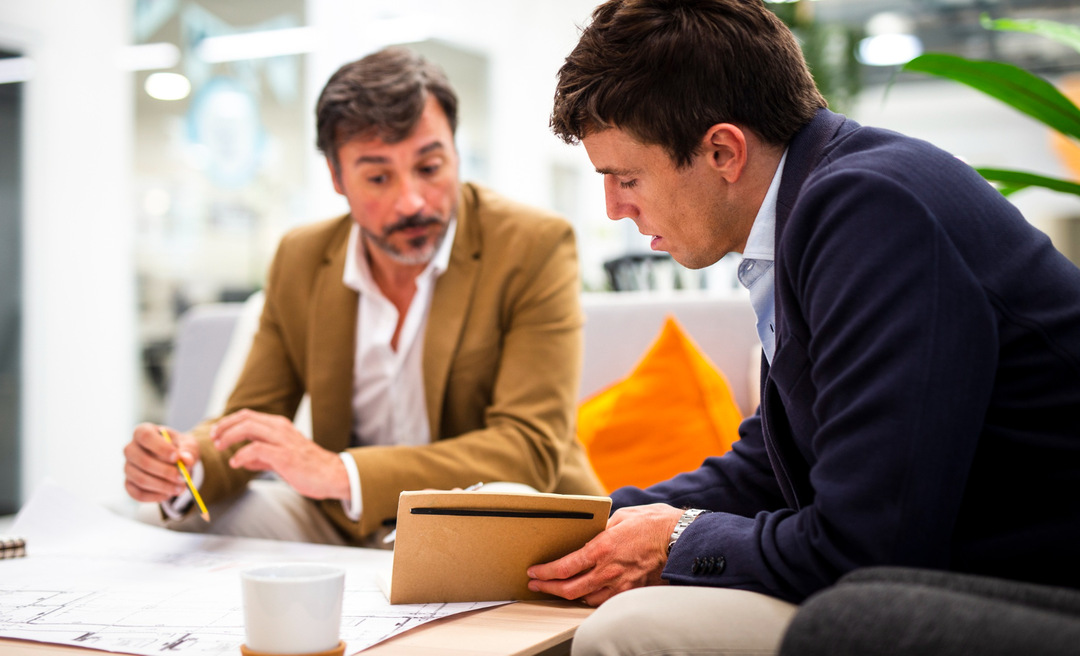 Two individuals discussing documents in an office, symbolizing planning for a trailer rental business.