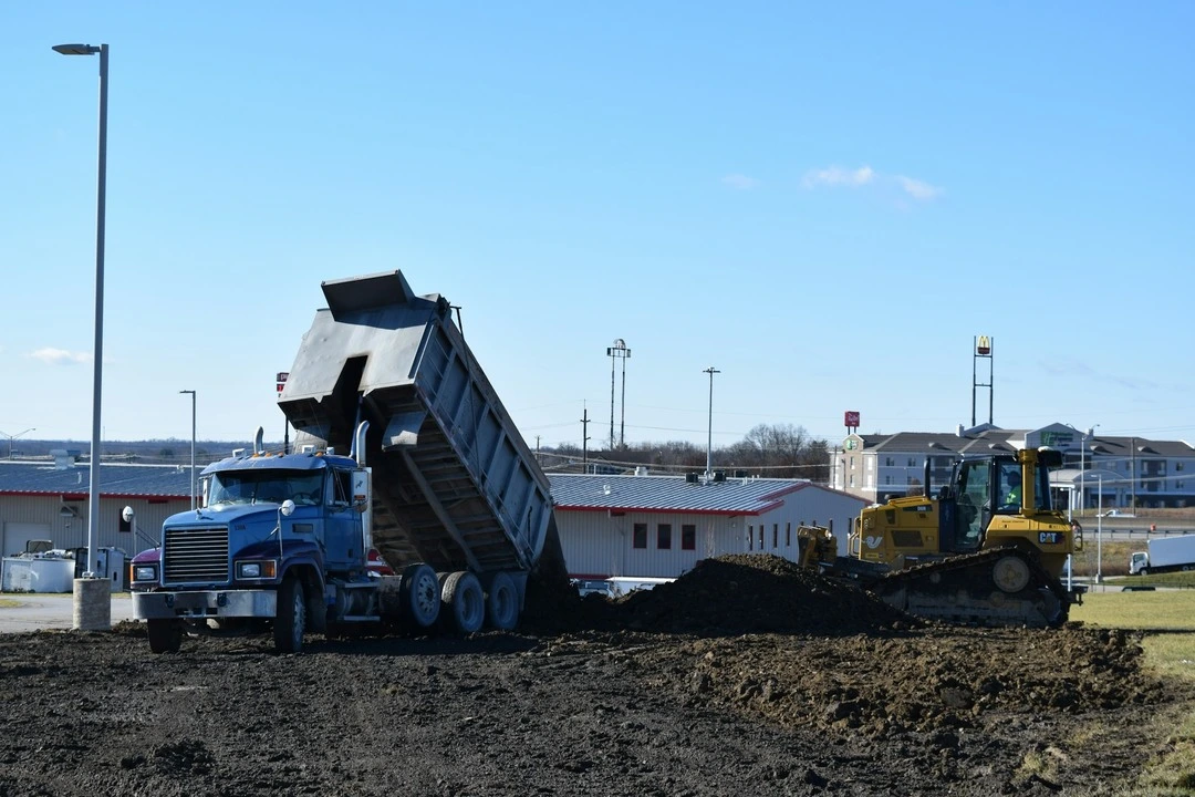 Blue dump truck unloading soil.
