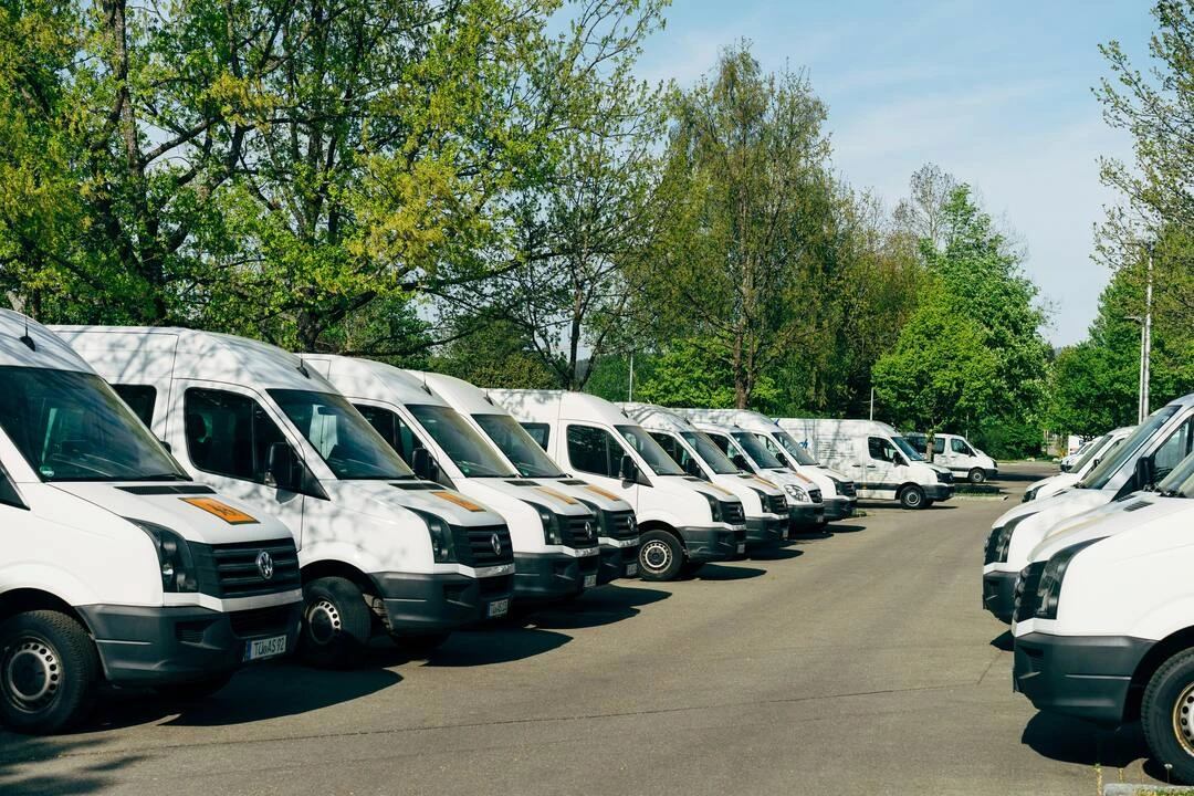 Multiple white vans are parked neatly, highlighting a well-organized rental fleet.