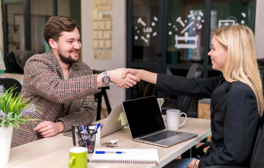 Happy client shaking hands with service provider in a modern workspace.