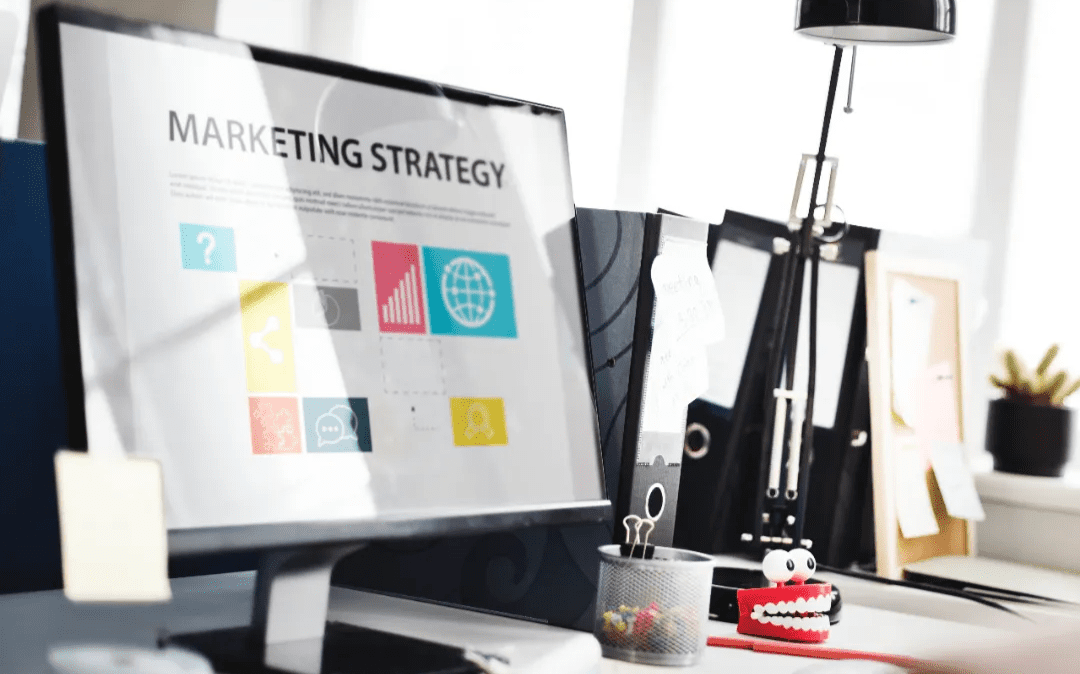 Computer screen displaying marketing strategy with colorful icons on a desk
