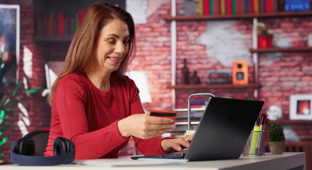 Woman smiling while making an online purchase on her laptop using a credit card