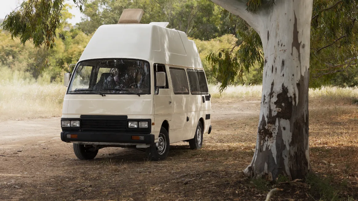 Campervan rental option parked in nature with tall trees